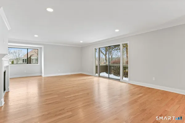 a view of an empty room with wooden floor fireplace and a window