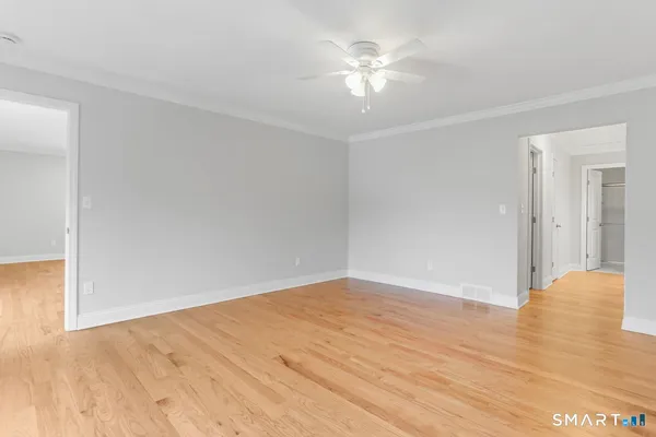a view of an empty room with wooden floor and a window
