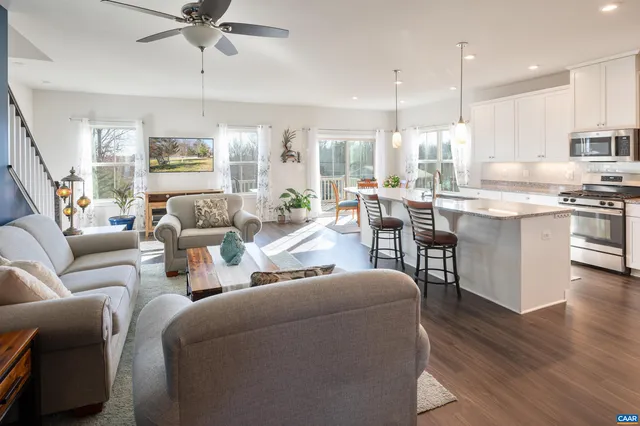 a living room with furniture and a dining table with potted plants