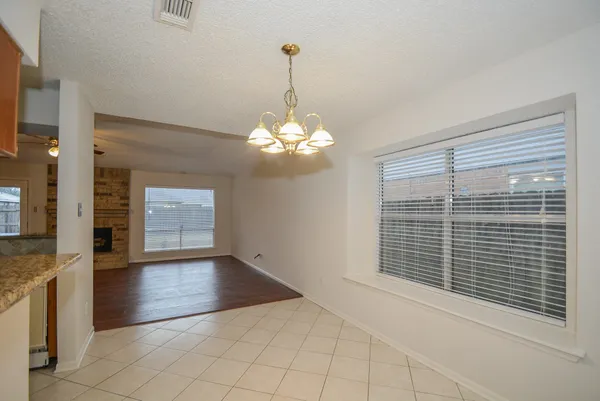 a view of an empty room with window wooden floor and kitchen