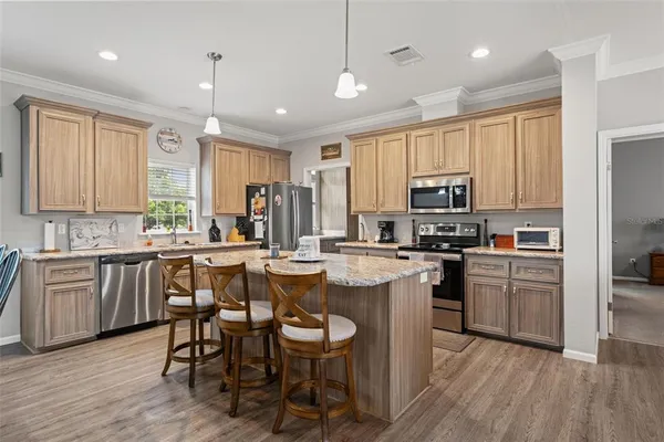 a kitchen with kitchen island granite countertop wooden floors appliances and white cabinets