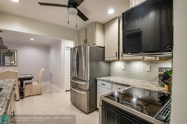 a kitchen with stainless steel appliances granite countertop a refrigerator a stove and a sink