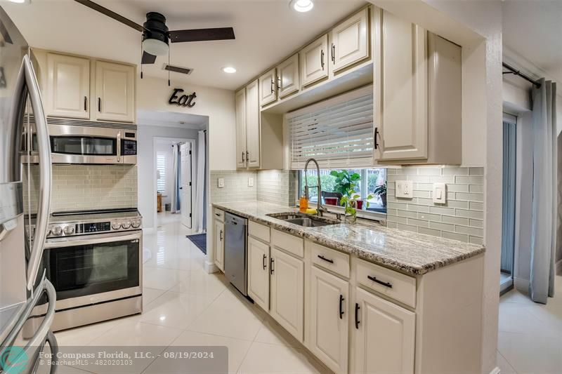 Undisclosed Address Pompano Beach, FL 33062 - Photo 18 of 63 a kitchen with stainless steel appliances granite countertop a stove a sink and a microwave