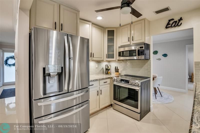 Undisclosed Address Pompano Beach, FL 33062 - Photo 19 of 63 a kitchen with stainless steel appliances granite countertop a stove a refrigerator and a microwave