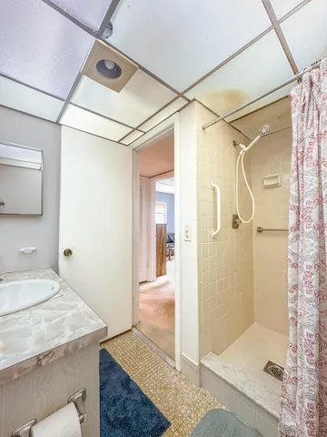 a bathroom with a sink shower and a mirror