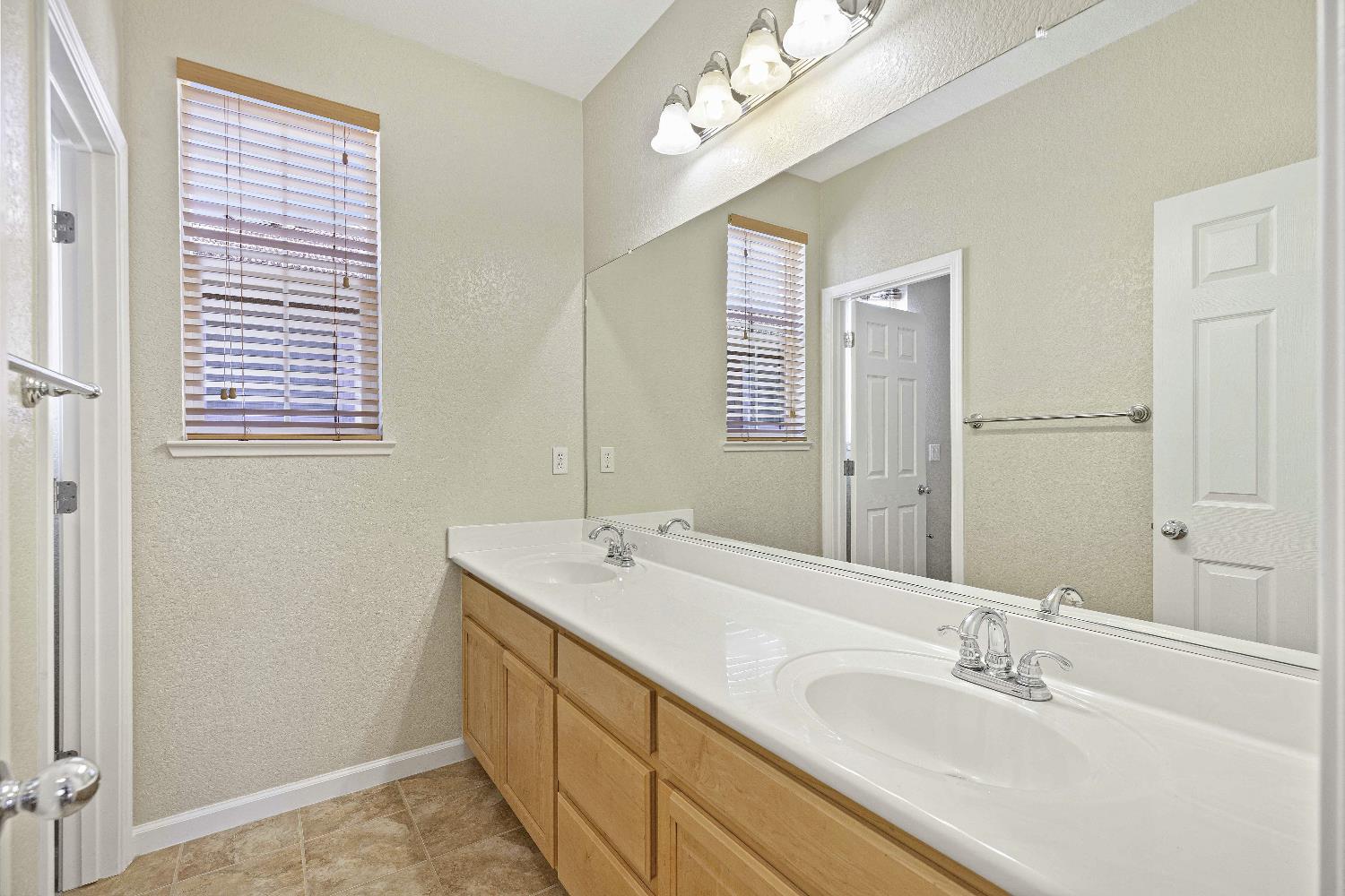 9397 Vintner Circle Patterson, CA 95363 - Photo 17 of 38 a bathroom with a double vanity sink and a mirror