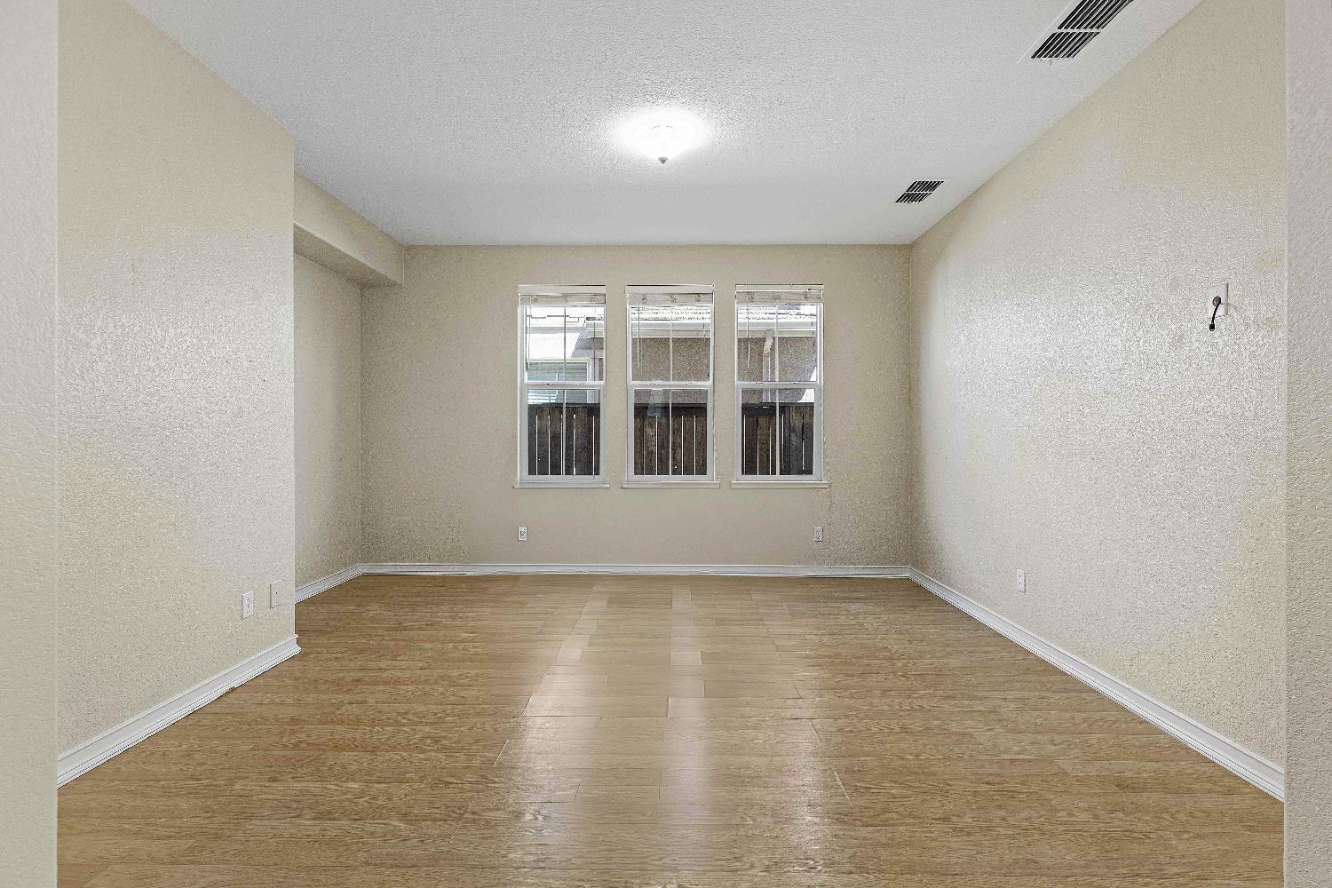 9397 Vintner Circle Patterson, CA 95363 - Photo 3 of 38 an empty room with wooden floor and windows