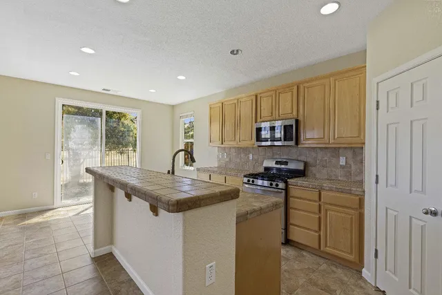 a kitchen with stainless steel appliances granite countertop a stove a sink and a microwave