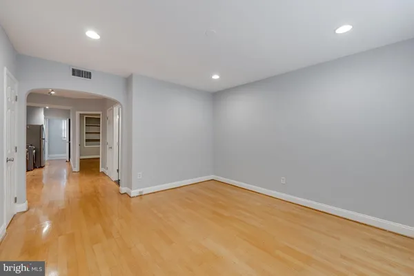 an empty room with wooden floor and natural light