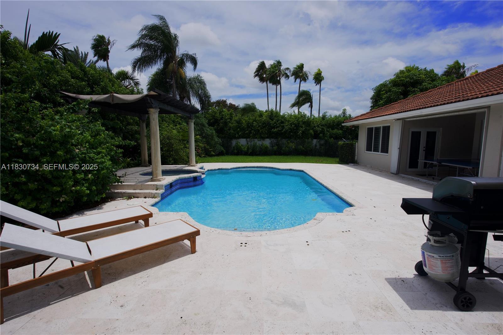 12401 Southwest 77th Street, Unit 12401 Miami, FL 33183 - Photo 20 of 95 a view of swimming pool with lounge chair and dinning table under an umbrella