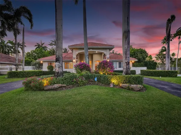 a front view of a house with garden and a bench