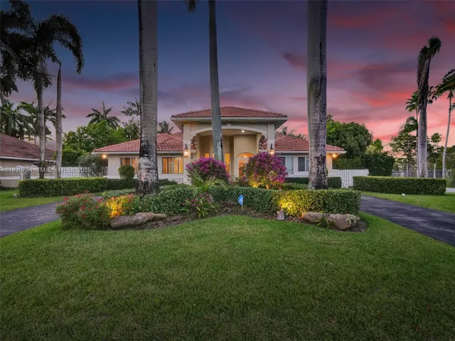 a front view of a house with garden and a bench