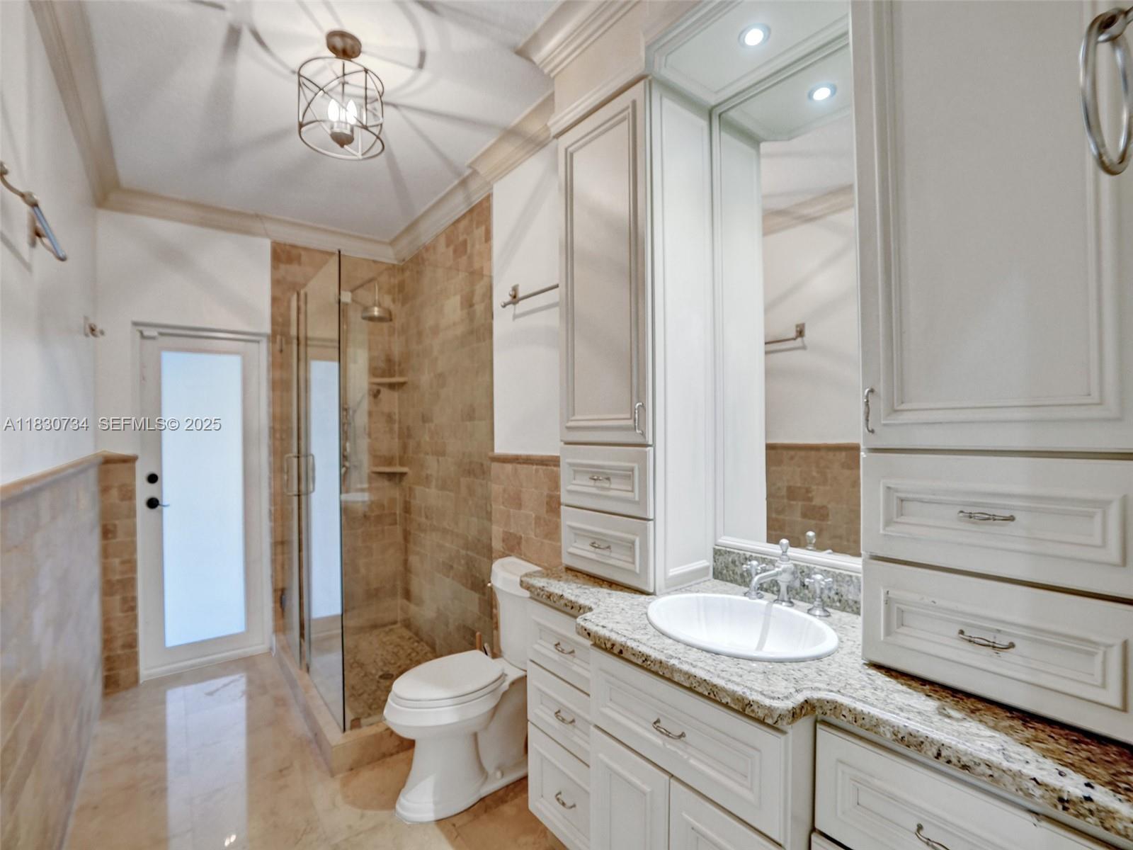 12401 Southwest 77th Street, Unit 12401 Miami, FL 33183 - Photo 86 of 95 a bathroom with a granite countertop sink a toilet a mirror and shower