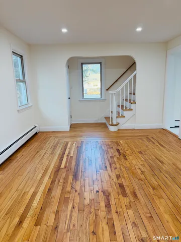 a view of an empty room with wooden floor and a window