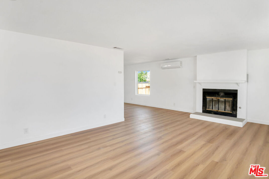 15376 Washoan Road Apple Valley, CA 92307 - Photo 28 of 40 an empty room with wooden floor fireplace and windows