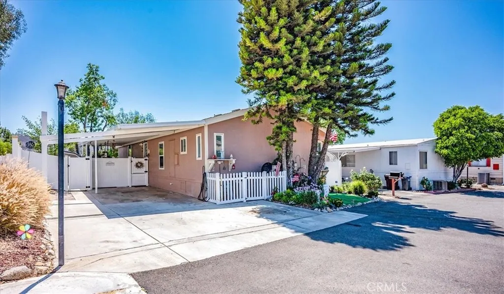 15181 Van Buren, Unit 178 Riverside, CA 92504 - Photo 1 of 52 a front view of a house with a garden and trees