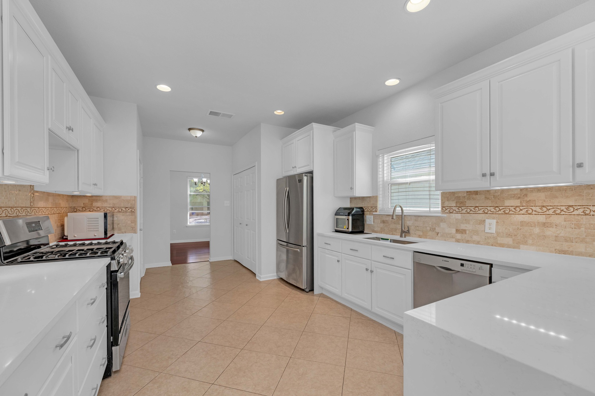 12528 Labrador Cove Austin, TX 78729 - Photo 18 of 40 Kitchen: Spacious and well designed with quartz countertops, white cabinetry, stainless steel appliances, and a gas range. Open layout with generous prep space, abundant storage, and seamless flow to adjacent living and dining areas.