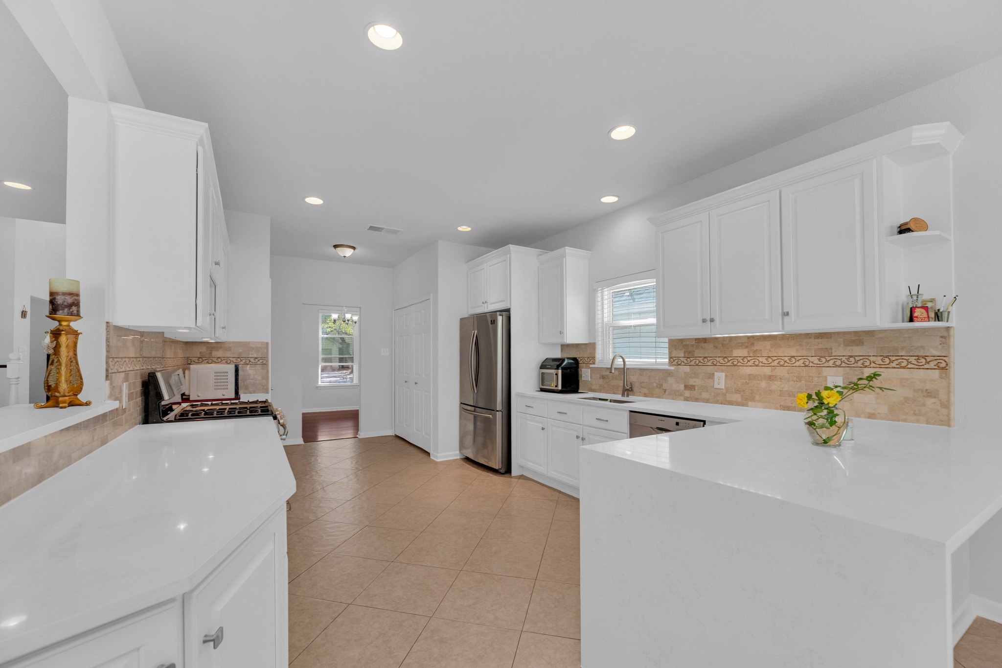 12528 Labrador Cove Austin, TX 78729 - Photo 19 of 40 Kitchen: Spacious and well designed with quartz countertops, white cabinetry, stainless steel appliances, and a gas range. Open layout with generous prep space, abundant storage, and seamless flow to adjacent living and dining areas.