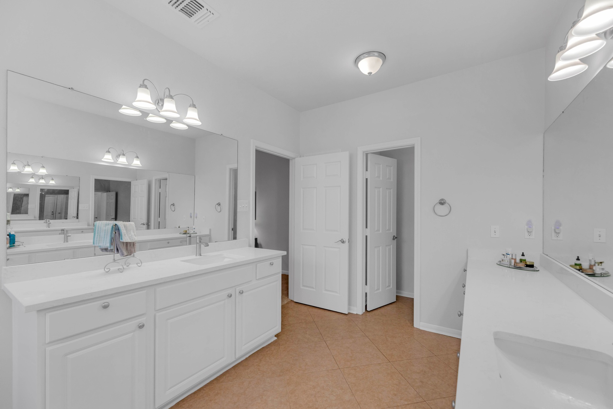 12528 Labrador Cove Austin, TX 78729 - Photo 29 of 40 Primary Bath: Expansive layout with dual vanities, quartz countertops, and ample storage. Bright and functional design with large mirrors and dedicated space for everyday convenience.