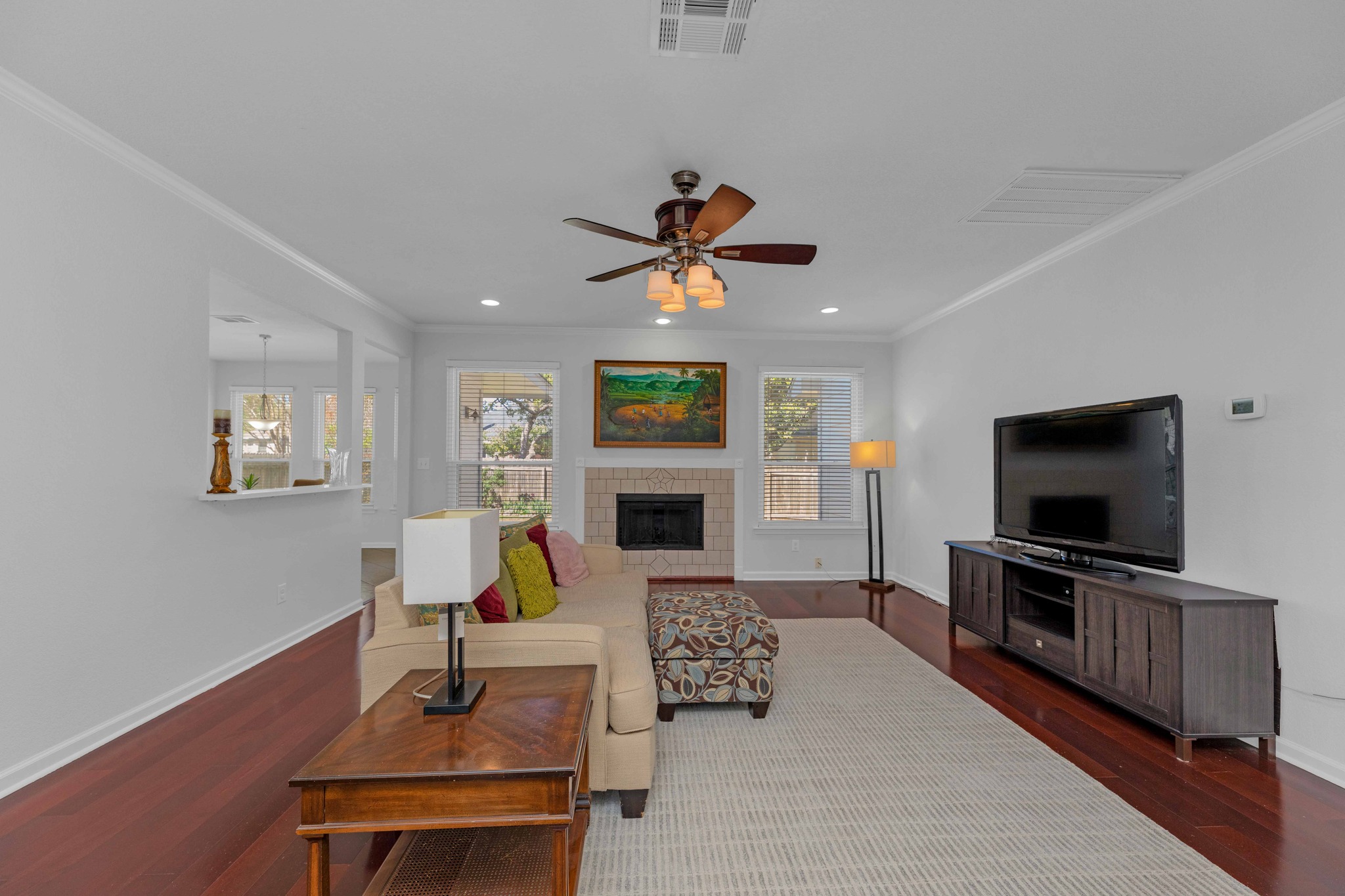 12528 Labrador Cove Austin, TX 78729 - Photo 9 of 40 Family Room: Light filled and spacious living area with rich wood flooring, a central fireplace, and an open connection to the kitchen. Designed for comfortable everyday living and effortless entertaining.