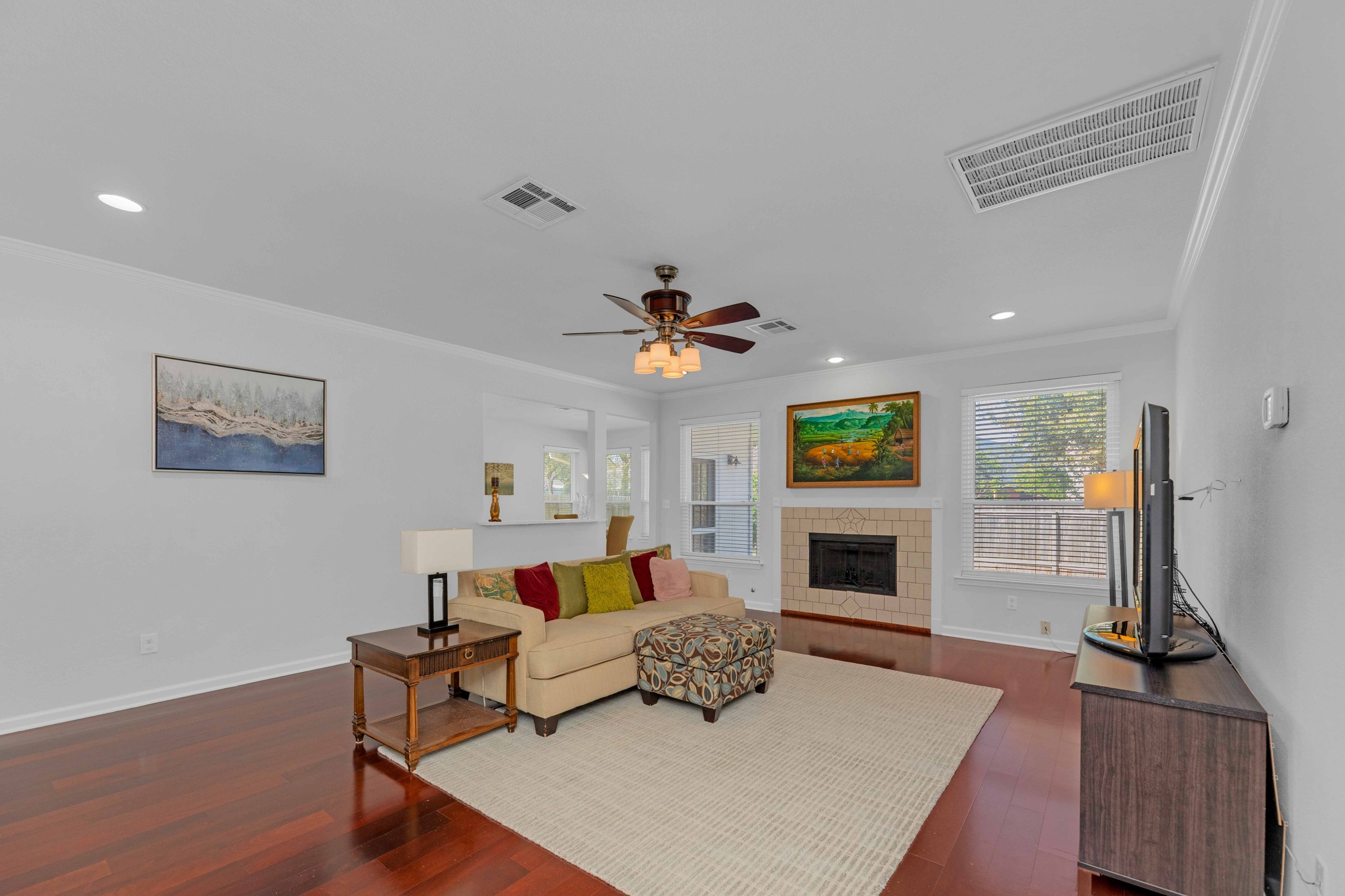 12528 Labrador Cove Austin, TX 78729 - Photo 10 of 40 Family Room: Expansive living area with rich wood flooring, fireplace centerpiece, and abundant natural light. Open to the kitchen for seamless flow, offering a comfortable and functional space for both everyday living and entertaining.