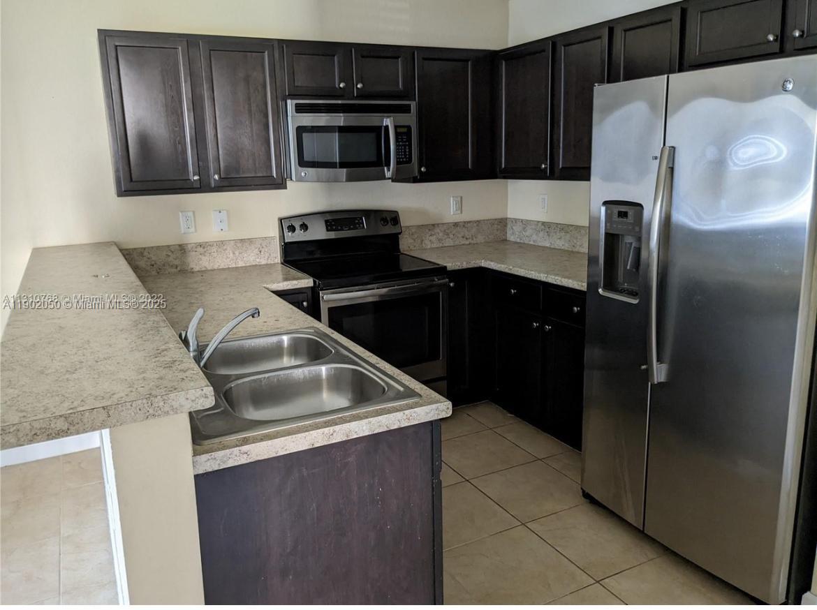 22411 Southwest 88th Place, Unit 926 Cutler Bay, FL 33190 - Photo 2 of 16 a kitchen with a refrigerator sink and microwave