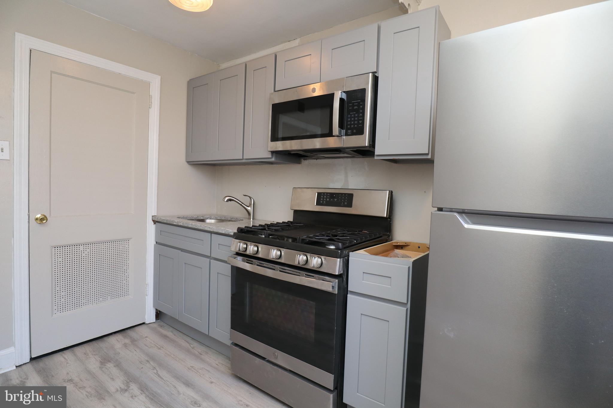 6335 Carnation Street, Unit 2 Philadelphia, PA 19144 - Photo 28 of 35 a kitchen with stainless steel appliances a white cabinet and a stove top oven