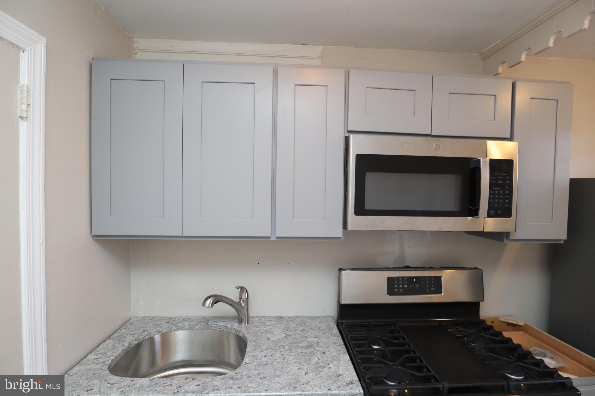 6335 Carnation Street, Unit 2 Philadelphia, PA 19144 - Photo 29 of 35 a kitchen with granite countertop white cabinets stainless steel appliances and sink