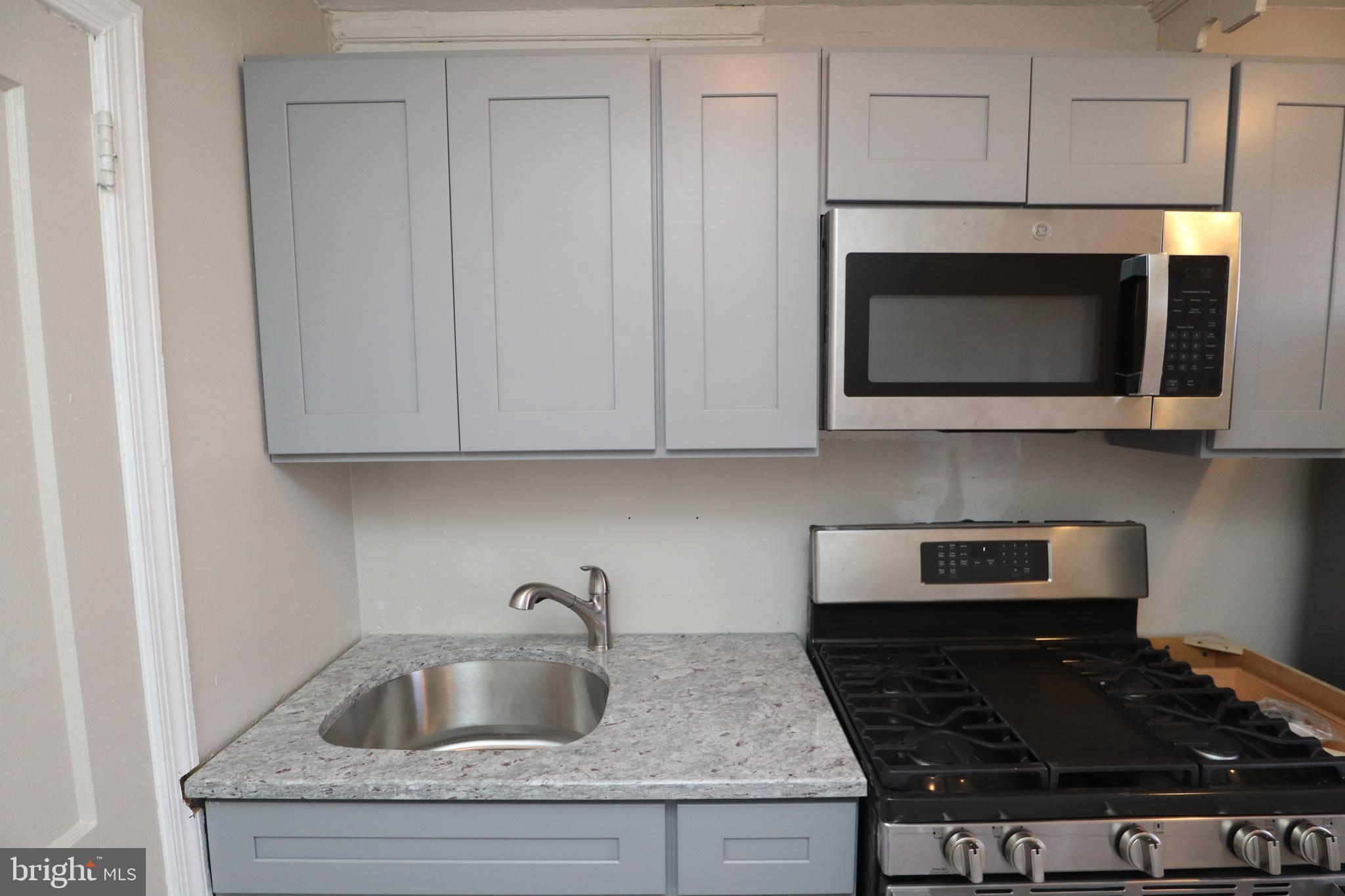6335 Carnation Street, Unit 2 Philadelphia, PA 19144 - Photo 30 of 35 a kitchen with granite countertop white cabinets stainless steel appliances and a sink