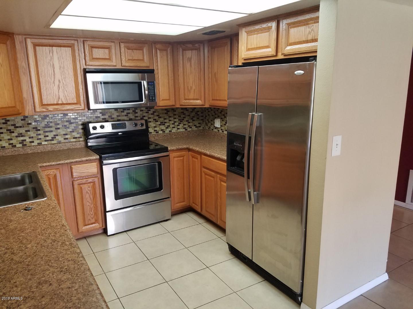 7830 East Camelback Road, Unit 212 Scottsdale, AZ 85251 - Photo 2 of 45 a kitchen with granite countertop a refrigerator and a stove top oven