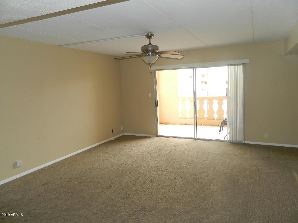 7830 East Camelback Road, Unit 212 Scottsdale, AZ 85251 - Photo 5 of 45 an empty room with windows and chandelier fan