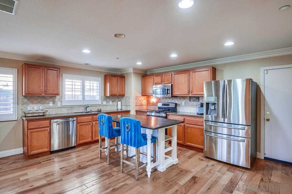 a kitchen with stainless steel appliances granite countertop wooden floors and wooden cabinets