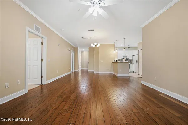 a view of a room with wooden floors and kitchen view