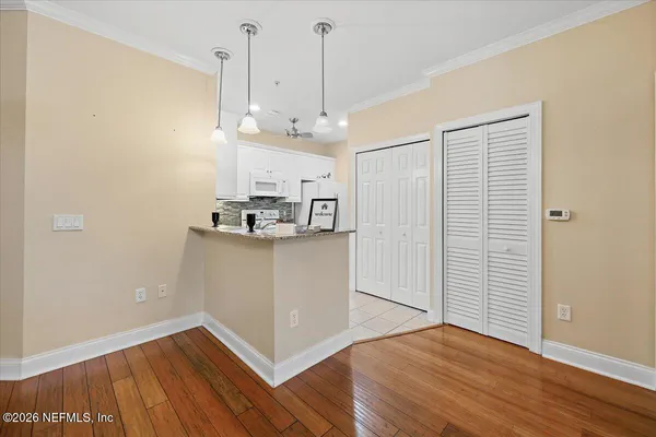 a view of an empty room with wooden floor and a window