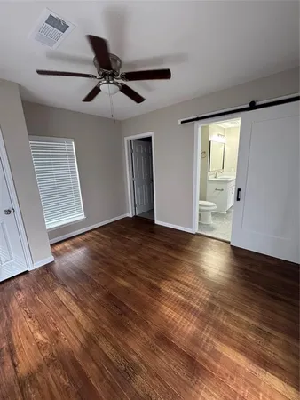 an empty room with wooden floor fan and windows