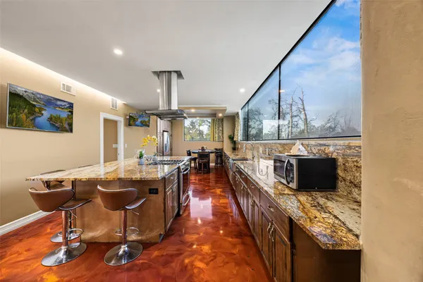 a view of a kitchen with kitchen island stainless steel appliances wooden floor dining table and chairs