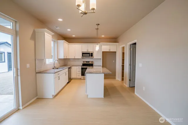 a large kitchen with a refrigerator a sink dishwasher a stove and a refrigerator with wooden floor