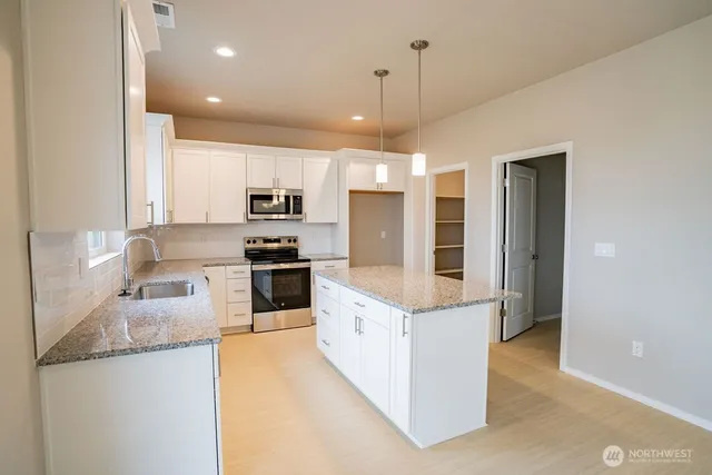 a large kitchen with stainless steel appliances granite countertop a stove and a refrigerator