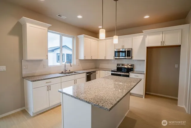 a kitchen with granite countertop a center island a sink stainless steel appliances and cabinets