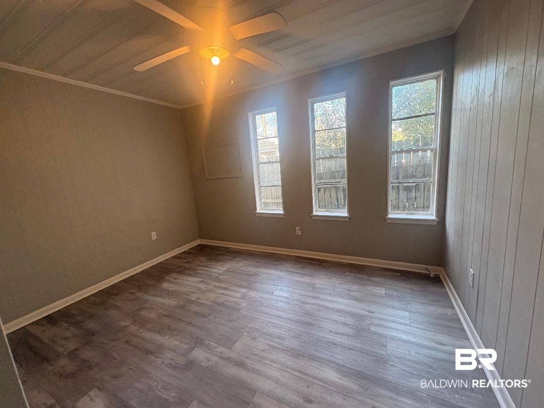 9330 Pinewood Avenue, Unit S 1 2 3 4 Elberta, AL 36530 - Photo 10 of 12 Spare room featuring wooden walls, wood finished floors, plenty of natural light, ceiling fan, and crown molding