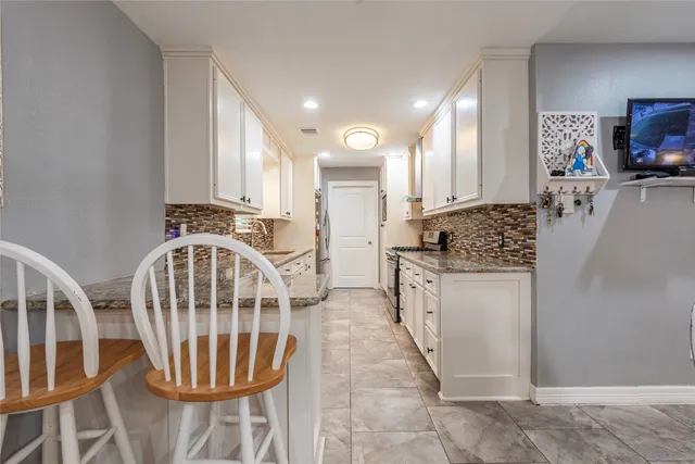 a kitchen with granite countertop a sink a stove a washer and dryer