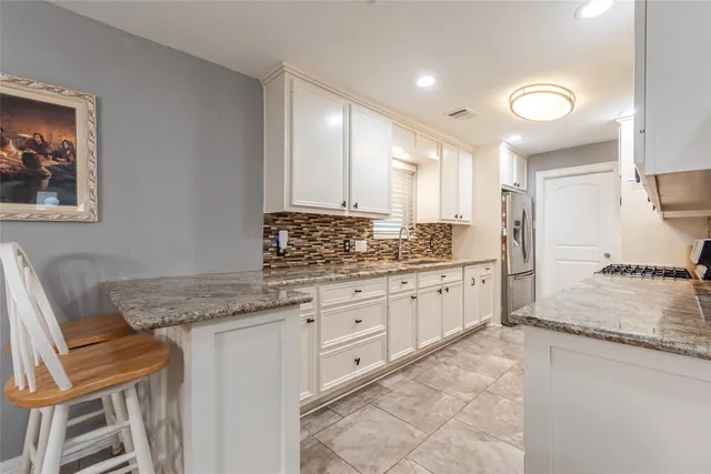 a kitchen with granite countertop a sink and white cabinets