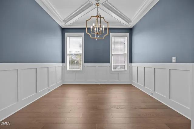 a view of an empty room with wooden floor and stairs