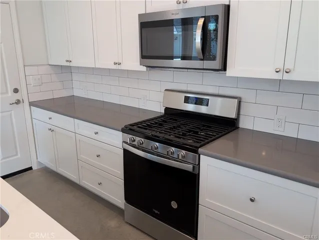 a kitchen with granite countertop white cabinets and stainless steel appliances