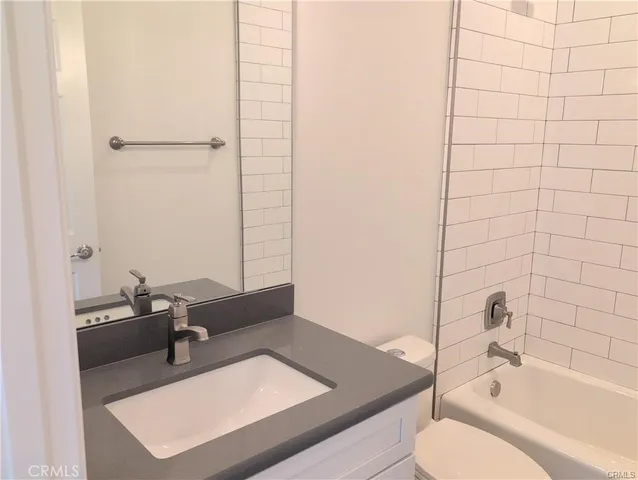 a bathroom with a tub sink vanity and toilet