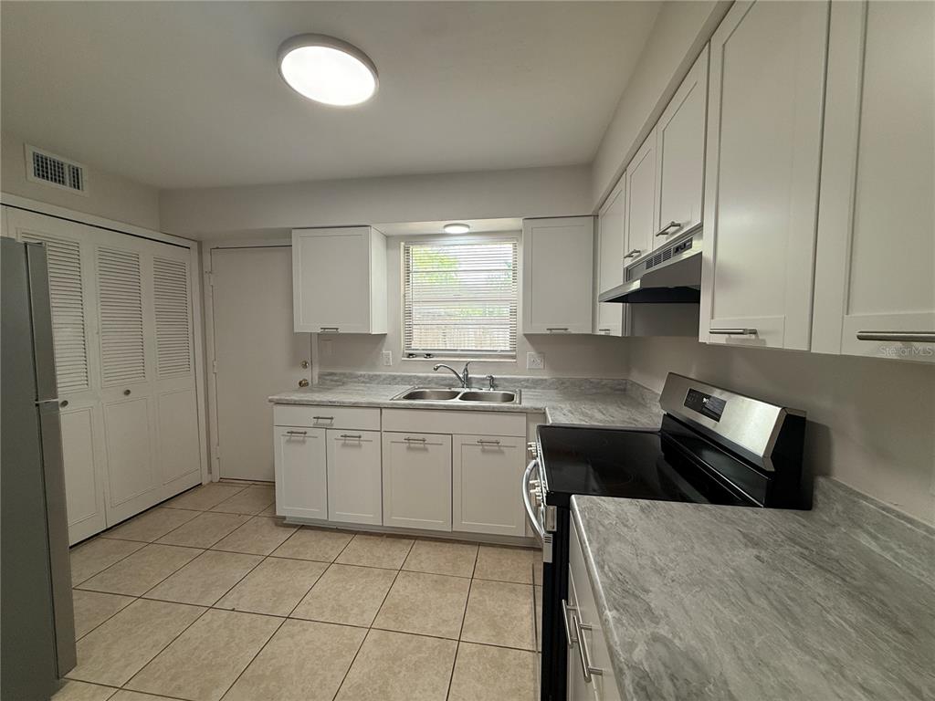 6030 Southwest 12th Place, Unit 2 Gainesville, FL 32607 - Photo 3 of 7 a kitchen with granite countertop white cabinets and white appliances