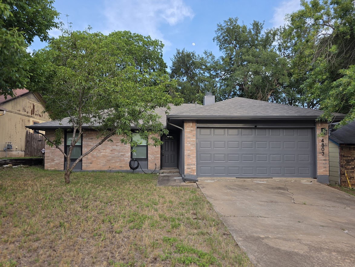 4803 Peach Grove Road Austin, TX 78744 - Photo 1 of 22 a front view of a house with a yard and garage