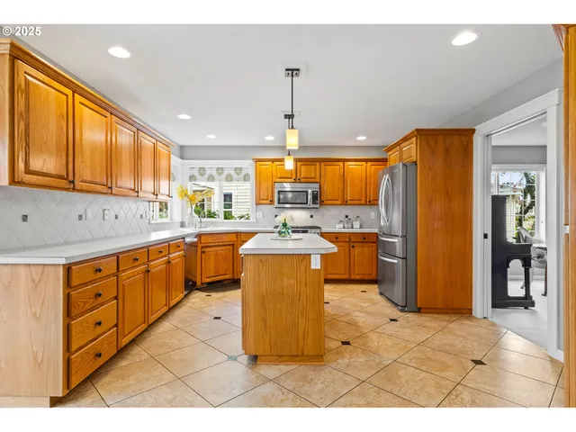 a kitchen with stainless steel appliances granite countertop a sink a stove a refrigerator cabinets and living room view