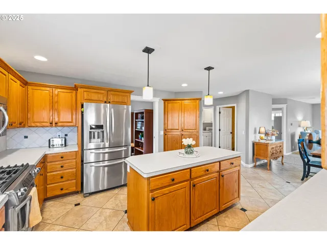 a kitchen with stainless steel appliances kitchen island granite countertop a sink a stove and a refrigerator