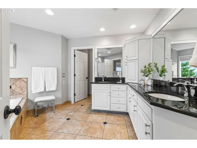 a large white kitchen with a sink and a large mirror